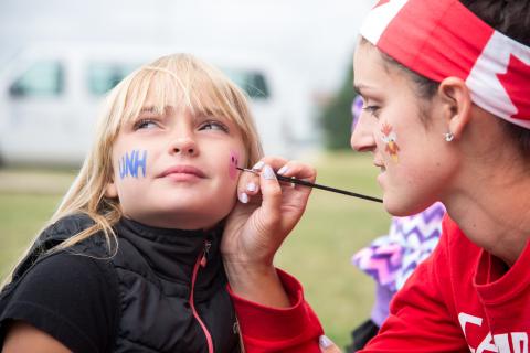 Camp counselor face painting a camper