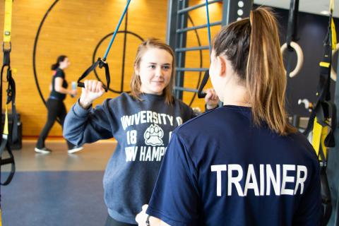 personal trainer assisting student in workout