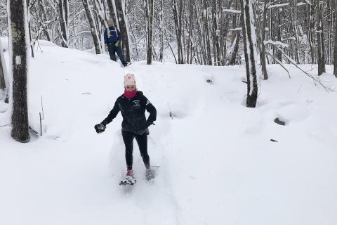 Student snowshoeing in winter woods