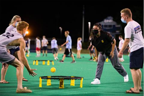 students with masks playing spikeball
