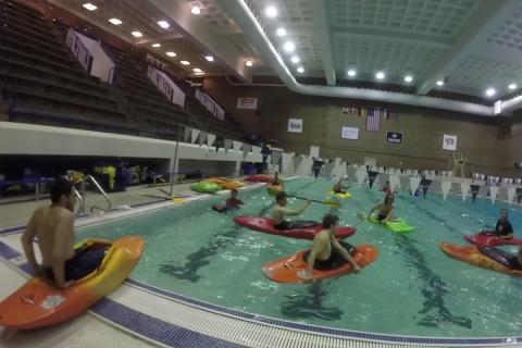 students in colorful kayaks in the indoor pool