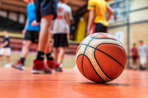 basketball on the floor of the gym, children gathering in background