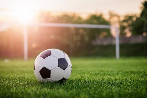Soccer ball on field in front of soccer goal.
