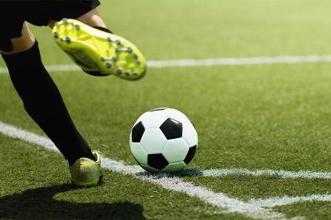Person kicking a soccer ball.