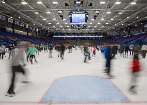 Wide shot of people skating on the Whittemore Center ice. 